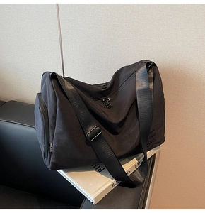Detalle del bolso tote de lona negra con bolsillo lateral y correa ajustable