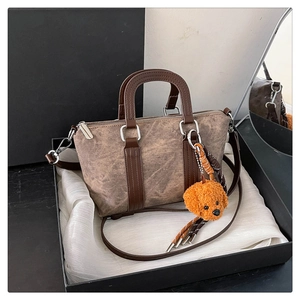 Detail of retro tan Boston bag with plush dog charm on premium white silk lining