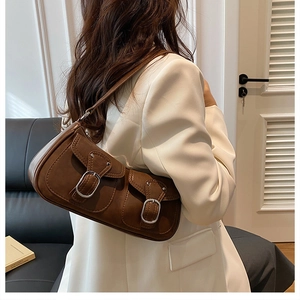 Brown vintage faux leather underarm bag with silver buckles shown on white blazer