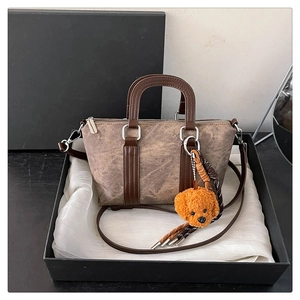 Detail of vintage brown mini boston bag with matte leather texture and plush bear charm