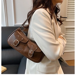 Close-up of brown vintage shoulder bag featuring dual pockets and silver metal buckles