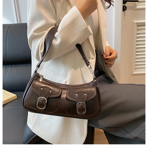 Detail of dark brown leather handbag with double pockets and silver metal buckles