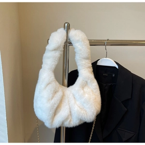 Close-up of white faux fur cloud bag with elegant gold metal chain strap on a hanger