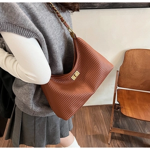 Detail of brown pleated leather hobo bag with gold twist lock and woven chain strap