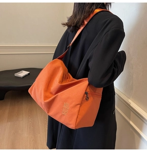 Bolso bandolera naranja de gran capacidad con texto MUL AIDI ON mostrado en modelo