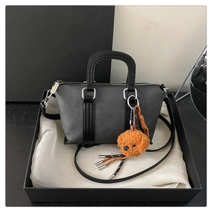 Detail view of leather handbag with silver hardware and a cute teddy dog charm in a gift box