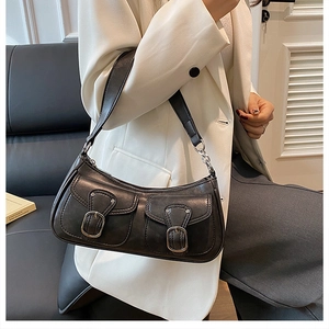 Detail of black leather shoulder bag featuring silver metal buckles and dual front pockets
