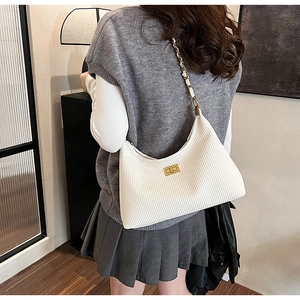 Detailed view of the white pleated bucket bag with a gold chain strap and turn-lock