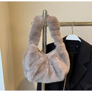 Detail of light brown faux fur cloud bag with gold chain strap on stylish blazer