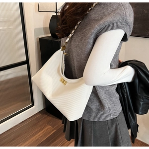 Close-up of white pleated hobo bag with gold chain strap and metal turn-lock closure