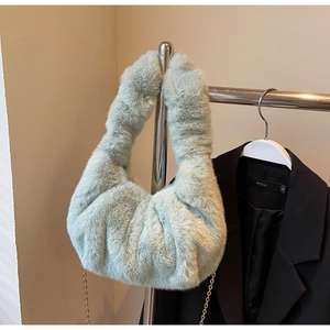 Detail shot of light green faux fur handbag with golden chain on a hanger