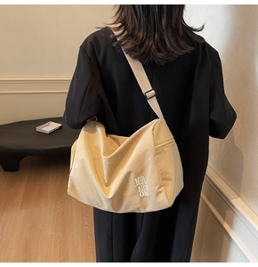 Detalle de bolso tote de lona beige con correa ajustable y cierre de cremallera en modelo