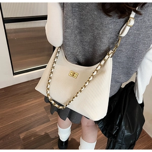 Detail of cream pleated shoulder bag featuring a gold twist lock and metal chain strap