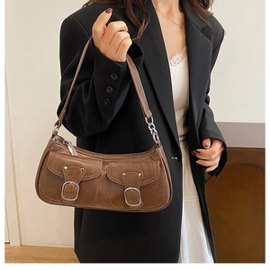 Brown retro underarm bag with metal buckle pockets shown worn by a model