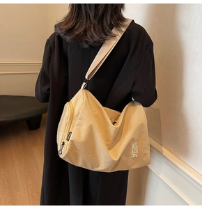 Detalle de bolso bandolera de lona beige con correa ancha ajustable y bolsillo lateral con cremallera