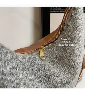Nahaufnahme des goldener Reißverschlusses der grauen Plüschtasche mit braunem Lederbesatz