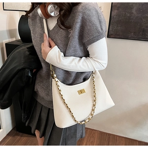 Detail of cream pleated shoulder bag featuring gold chain and metallic turn-lock closure