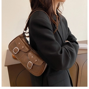Detail view of brown retro underarm bag with double utility pockets and silver buckles