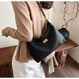 Detail of black pleated leather underarm bag with gold chain strap and metal lock