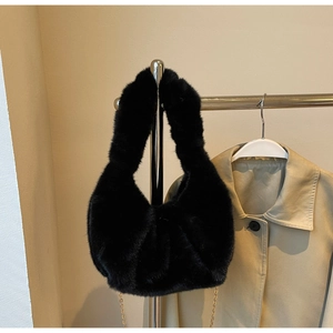 Detail of black faux fur crescent bag with gathered texture and elegant gold chain