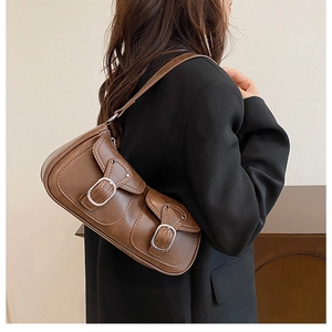 Close-up of vintage brown leather underarm bag with double front flap pockets on model