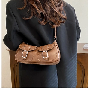 Brown faux leather shoulder bag featuring dual front pockets and silver metal buckles