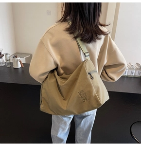 Detalle de bandolera de lona caqui que muestra el bordado MULAIDION y bolsillo lateral