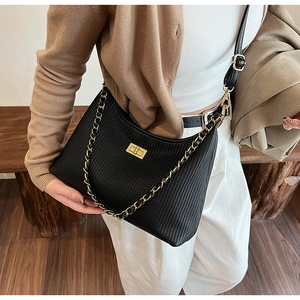 Detail of black pleated shoulder bag featuring gold chain and turn-lock closure