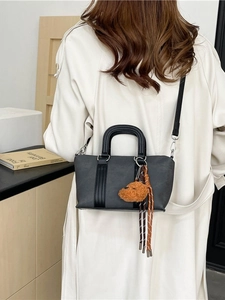 Retro grey boston bag with plush bear charm and striped strap shown on model back