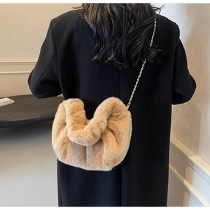 Detail of soft khaki faux fur cloud bag with gold chain strap on black winter coat