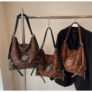 Detailansicht der Leopard-Print-Einkaufstaschen mit M-Metalllogo und Kettenelementen