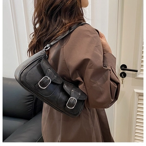 Detail of black faux leather underarm bag with double front pockets and silver buckles