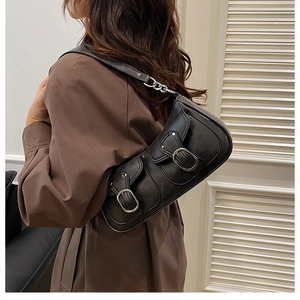 Detail of matte black underarm bag featuring dual pockets with silver buckles and chain strap
