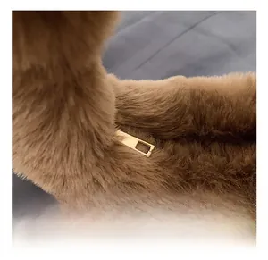 Detailed macro view of premium gold metal zipper on brown plush dumpling handbag