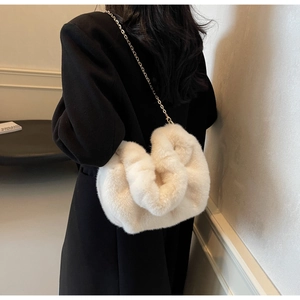 Detail of soft cream faux fur crossbody bag with elegant gold metal chain strap on model