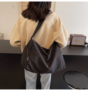 Detalle del bolso tote grande de nailon negro que muestra la etiqueta lateral y la textura