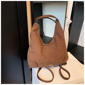 Detail view of brown suede texture on a convertible backpack with top handle and straps