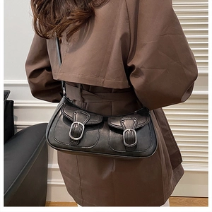 Detail view of a black shoulder bag with dual front pockets and silver metal buckles