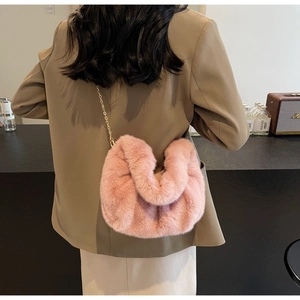 Detail view of pink faux fur chain bag with plush pleated texture worn on shoulder