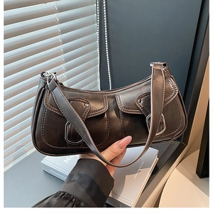 Detail of dark brown vintage underarm bag featuring dual pockets and large silver buckles