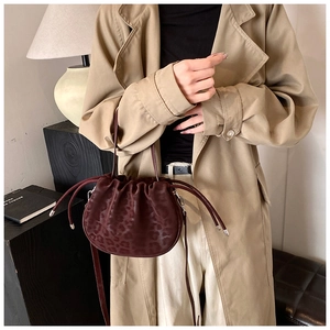 Detail der burgunderroten Bucket-Bag mit Leopardenmuster und Kordelzug am Modell