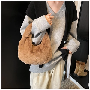 Brown plush hobo bag carried by hand, styled with a winter sweater for a cozy look