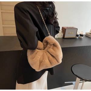 Chic brown faux fur cloud bag with gold chain strap styled in a cozy indoor setting