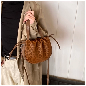 Detailaufnahme der Leoparden-Beuteltasche mit Lederriemen auf einem Trenchcoat