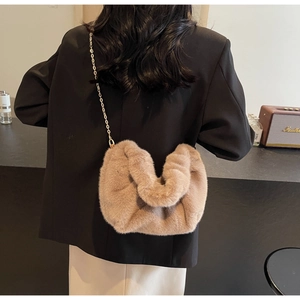 Detail view of taupe faux fur cloud crossbody bag with gold chain strap on model