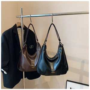 Detail view of brown and black faux leather underarm bags with metallic oval logo plates
