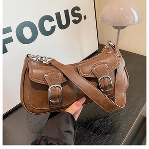 Detail of vintage brown leather handbag with silver buckles and dual front pockets