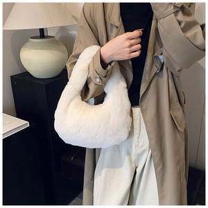 Detailed texture of white plush dumpling handbag held by a model for autumn winter style