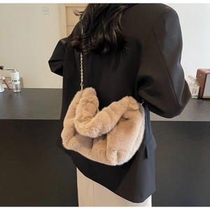 Detail of coffee brown faux fur crossbody bag with elegant gold chain strap worn by a model