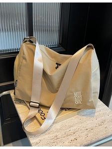 Bolso bandolera grande de lona caqui con bordado sobre mármol y fondo vintage retro